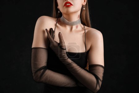 Foto de Hermosa mujer en vestido negro con mordeduras de amor en su cuello contra fondo oscuro - Imagen libre de derechos