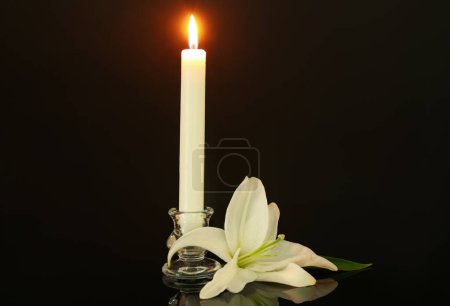 Foto de Flor de lirio blanco y vela encendida sobre fondo oscuro - Imagen libre de derechos