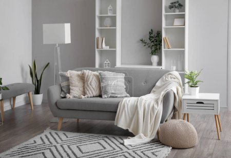 Interior of living room with grey sofa and shelving units