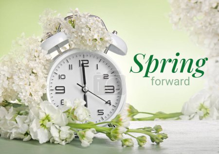 Foto de Reloj despertador y flores blancas sobre fondo verde. Primavera - Imagen libre de derechos
