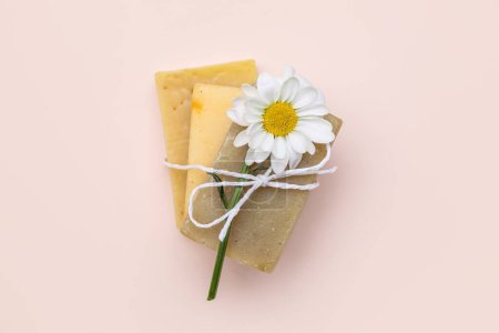 Soap bars with chamomile flower tied with rope on color background