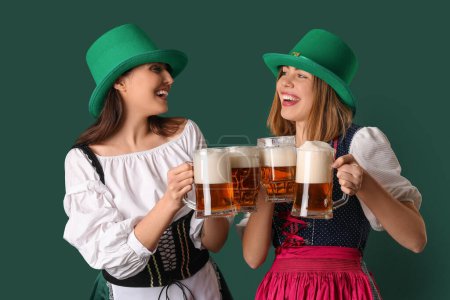 Téléchargez les photos : Irish waitresses with glasses of beer on green background. St. Patrick's Day celebration - en image libre de droit