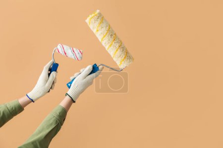 Téléchargez les photos : Peintre féminine avec rouleaux sur fond beige - en image libre de droit