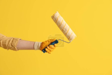 Téléchargez les photos : Travailleur avec rouleau de peinture sur fond jaune - en image libre de droit