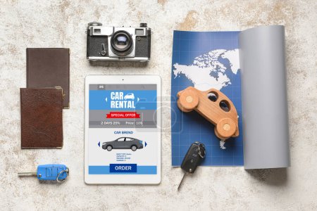 Téléchargez les photos : Tablette avec page ouverte du site de location de voiture, carte, clés, appareil photo et passeports sur fond clair - en image libre de droit