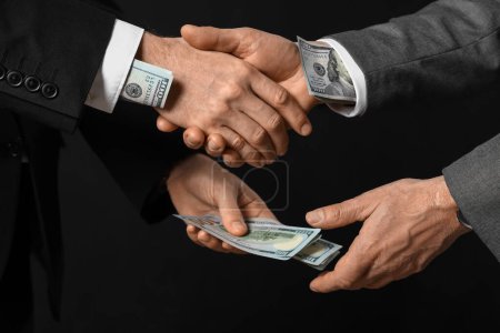 Photo for Men with bribe shaking hands on dark background, closeup - Royalty Free Image