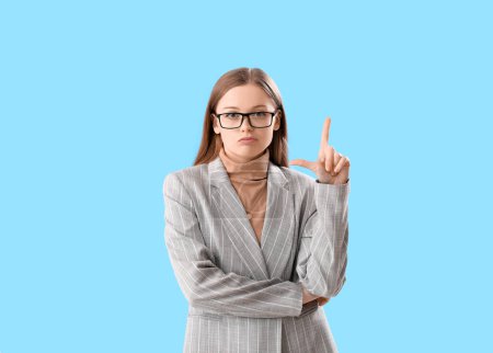 Photo for Young businesswoman showing loser gesture on blue background - Royalty Free Image
