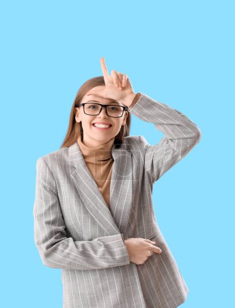 Photo for Young businesswoman showing loser gesture on blue background - Royalty Free Image