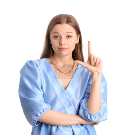 Photo for Young woman in dress showing loser gesture on white background - Royalty Free Image