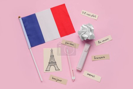 Französische Flagge mit französischen Worten, gezeichnetem Eiffelturm, Stiften und zerknittertem Papier auf rosa Hintergrund