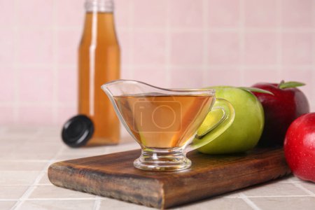 Téléchargez les photos : Bateau à sauce au vinaigre de cidre de pomme frais et fruits sur table carrelée rose - en image libre de droit