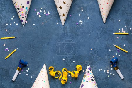 Foto de Marco hecho de sombreros de fiesta, silbatos, velas y confeti sobre fondo de color - Imagen libre de derechos