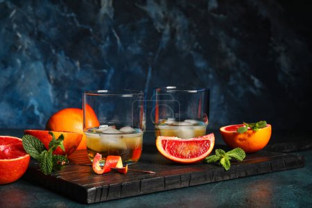 Foto de Vasos de ron con hielo, menta y naranja siciliana en la mesa - Imagen libre de derechos