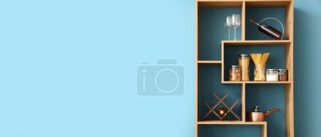 Photo for Wooden shelving unit with products near blue wall in kitchen. Banner for design - Royalty Free Image