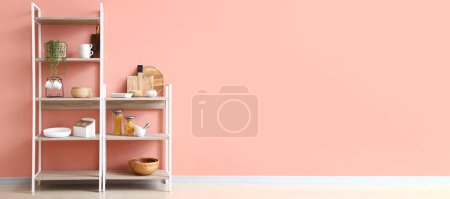 Shelving units with products and kitchen utensils near pink wall. Banner for design