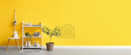 Téléchargez les photos : Intérieur du couloir moderne avec vêtements et accessoires sur étagère près du mur jaune. Bannière pour le design - en image libre de droit