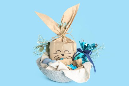 Foto de Cesta con bolsa de regalo de conejo de Pascua sobre fondo azul - Imagen libre de derechos