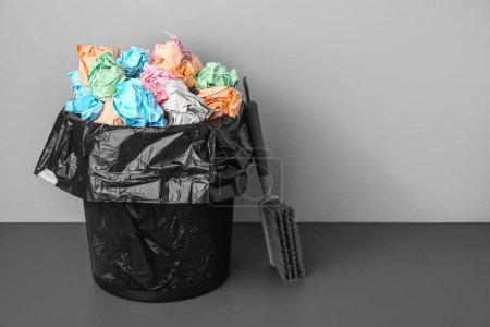 Photo for Rubbish bin with crumpled paper and brush near grey wall - Royalty Free Image