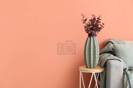 Téléchargez les photos : Vase with eucalyptus on table and grey sofa near pink wall - en image libre de droit
