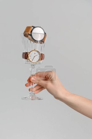 Foto de Mujer con cristal y elegantes relojes de pulsera sobre fondo gris - Imagen libre de derechos