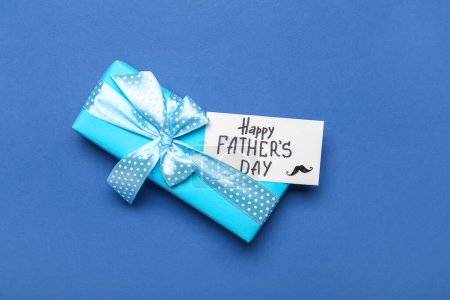 Gift box and card with text HAPPY FATHER'S DAY on color background