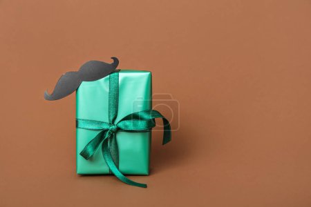 Photo for Beautiful gift box with paper mustache Father's Day celebration on color background - Royalty Free Image