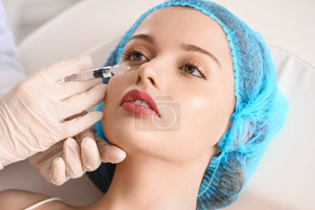 Mujer joven recibiendo inyección de relleno en salón de belleza