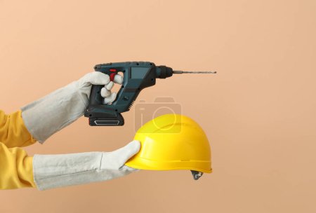 Téléchargez les photos : Constructeur féminin avec casque et perceuse sur fond beige - en image libre de droit
