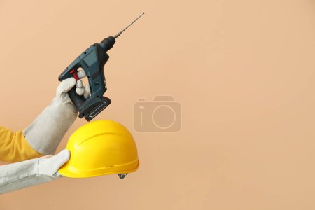 Téléchargez les photos : Constructeur féminin avec casque et perceuse sur fond beige - en image libre de droit