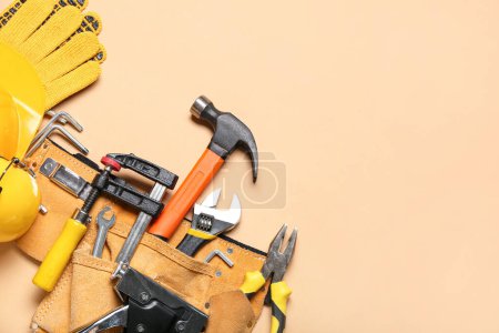 Pliers in belt with tools on beige background