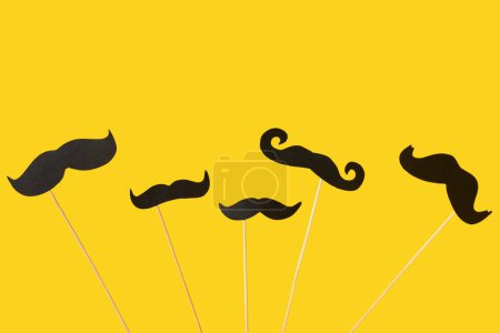 Photo for Set of different paper mustaches on yellow background - Royalty Free Image