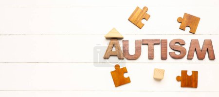 Photo for Word AUTISM and puzzle pieces on white wooden background with space for text - Royalty Free Image