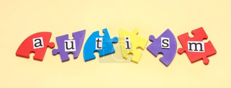 Photo for Word AUTISM and jigsaw puzzle pieces on beige background - Royalty Free Image
