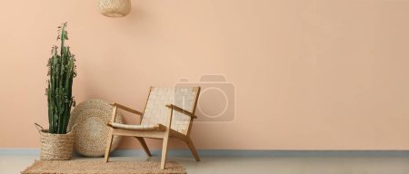 Photo for Cactus with knitted pouf and armchair near beige wall in room. Banner for design - Royalty Free Image