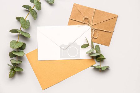 Téléchargez les photos : Composition avec enveloppes, cartes et branches d'eucalyptus sur fond blanc - en image libre de droit