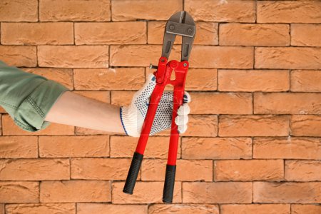 Photo for Worker with bolt cutter on brick background - Royalty Free Image