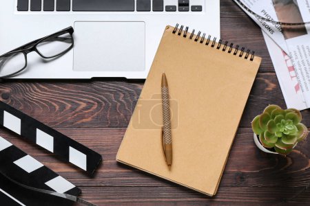 Photo for Notebook with laptop, eyeglasses and movie clapper on dark wooden background - Royalty Free Image