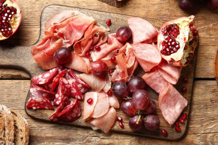 Photo for Board with assortment of tasty deli meats on wooden background - Royalty Free Image
