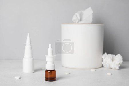 Photo for Bottles of drops with pills and tissue box on table near grey wall. Allergy concept - Royalty Free Image