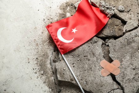 Stone debris with medical plasters and Turkish flag on light background. Turkey earthquake concept