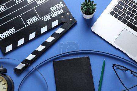 Photo for Notebook with movie clapper, film reel and laptop on blue background - Royalty Free Image