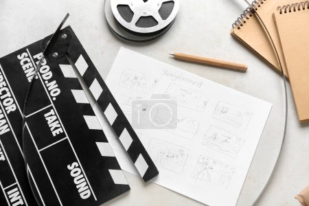 Filmklöppel mit Storyboard, Notizbüchern und Filmrolle auf hellem Hintergrund