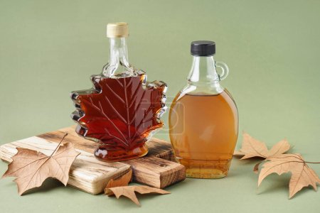 Photo for Bottles of maple syrup on green background - Royalty Free Image
