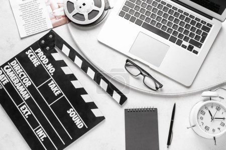 Filmklöppel mit Filmrolle, Brille und Laptop auf weißem Hintergrund