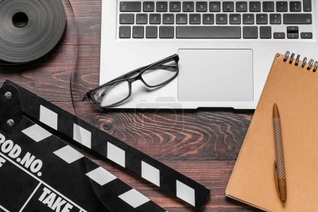 Photo for Notebook with laptop, film and movie clapper on dark wooden background - Royalty Free Image