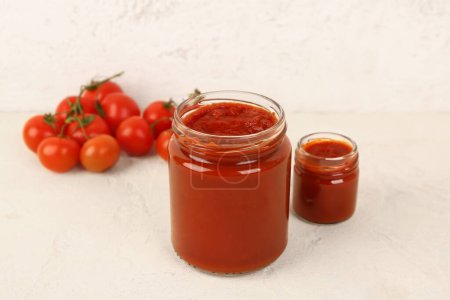 Frascos con sabrosa pasta de tomate sobre fondo claro