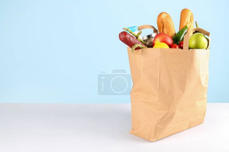 Papiertüte mit Gemüse, Obst, Wurst, Brot und Milch auf dem Tisch