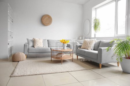 Interior of modern living room with cozy sofas and flower vase on coffee table