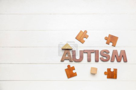 Photo for Word AUTISM with puzzle pieces and baby toys on white wooden background - Royalty Free Image