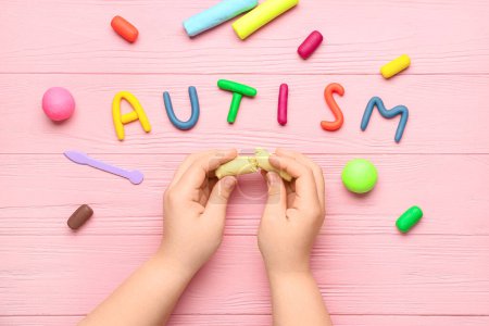 Photo for Child with plasticine and word AUTISM on pink wooden background - Royalty Free Image